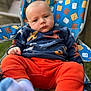 Ashtyn is registered to the contest to win money with this photo: baby, child, infant, blue_shirt, orange_pants, socks, chair, outdoor, patterned_chair, dinosaur_print, marshmallow_pattern, crackers_pattern, cute, portrait, seated, expression, young_child, casual_clothing, relaxed, daylight