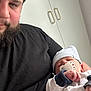 Samaël participe au concours pour gagner de l'argent avec cette photo : man, baby, pacifier, hat, beard, black_shirt, sleeping, indoor, cabinet, white_clothing, closeup, holding, resting, portrait, human, parent, child, cozy, calm, domestic