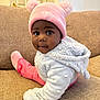 baby, beige_couch, child, close_up, couch, cozy, cute, face, hat, indoor, infant, looking, person, pink_hat, pom_poms, portrait, sitting, sweater, warm_clothing, white_sweater