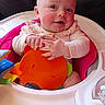 Sunniva is registered to the contest to win money with this photo: baby, child, high_chair, toy, headband, smile, happy, indoor, infant, clothing, face, hand, colorful, play, seat, person, cute, cheeks, young, expressive