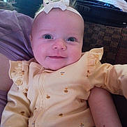 Sunniva is registered to the contest to win money with this photo: baby, smile, headband, yellow_outfit, infant, happy, face, person, closeup, indoor, child, cute, plush, sitting, portrait, soft_lighting, patterned_fabric, cozy, small_prints, young_child