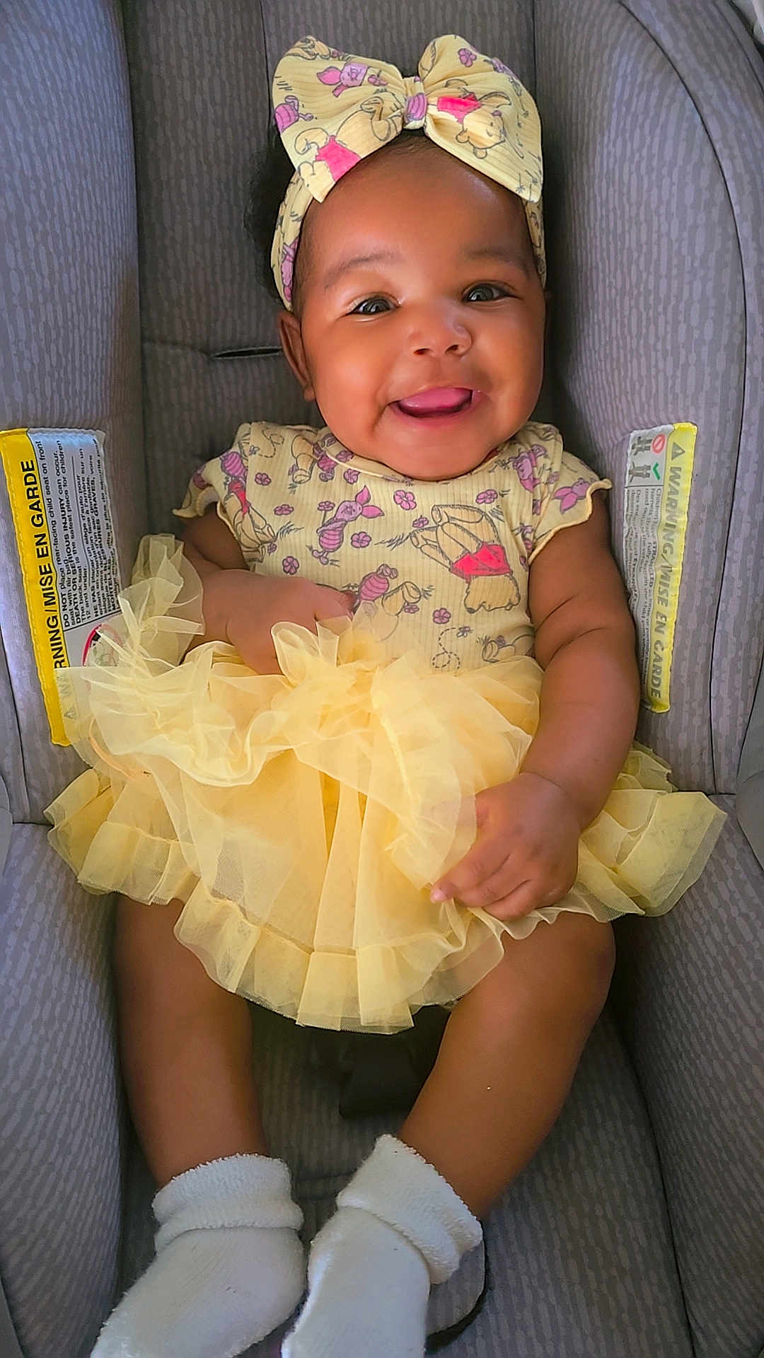 Eli'Yana joined the competition — help win amazing prizes! baby, child, smiling, headband, yellow_dress, car_seat, socks, cute, happy, infant, portrait, clothing, seated, toddler, playful, face, skin, person, baby_girl, adorable