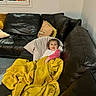 child, blanket, couch, leather, pillow, window, indoor, cozy, smiling, young_child, furniture, home, yellow, dark, relaxing, person, portrait, casual, comfort, living_room