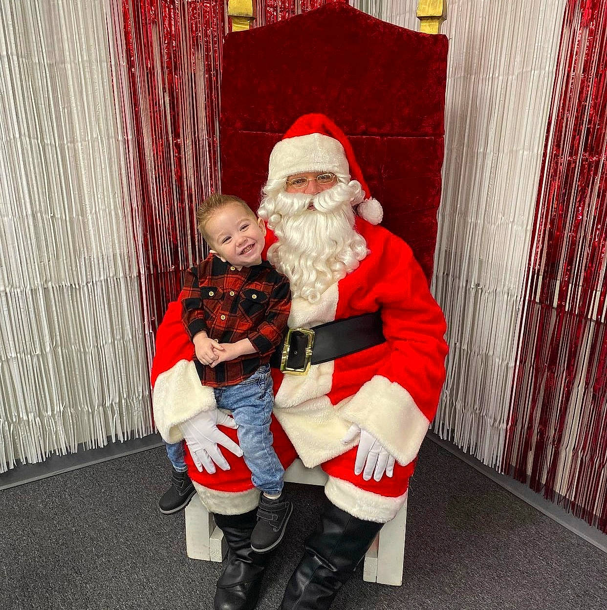 Gianni is registered to the contest to win money with this photo: beard, boot, carmine, christmas, christmas_eve, curtain, event, facial_hair, fictional_character, fun, fur, happy, hat, headwear, holiday, joy, lap, person, red, santa_claus