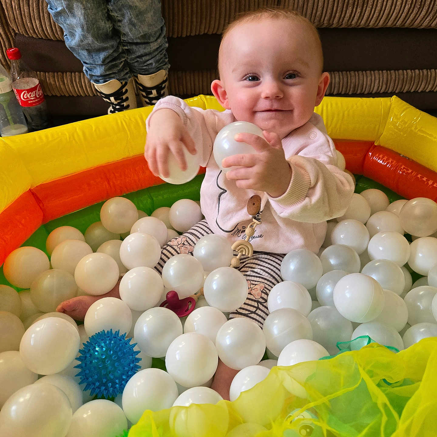 Ezmai joined the competition — help win amazing prizes! baby, ball_pit, boots, child, clothing, colorful, couch, face, happy, home, indoor, inflatable, jeans, person, plastic_balls, playtime, sitting, smiling, toys, young_child