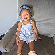 Magnolia is registered to the contest to win money with this photo: toddler, child, smile, dress, headband, blue, shoes, armchair, furniture, indoor, happy, person, footwear, cute, young_child, portrait, seated, clothing, hair, skin
