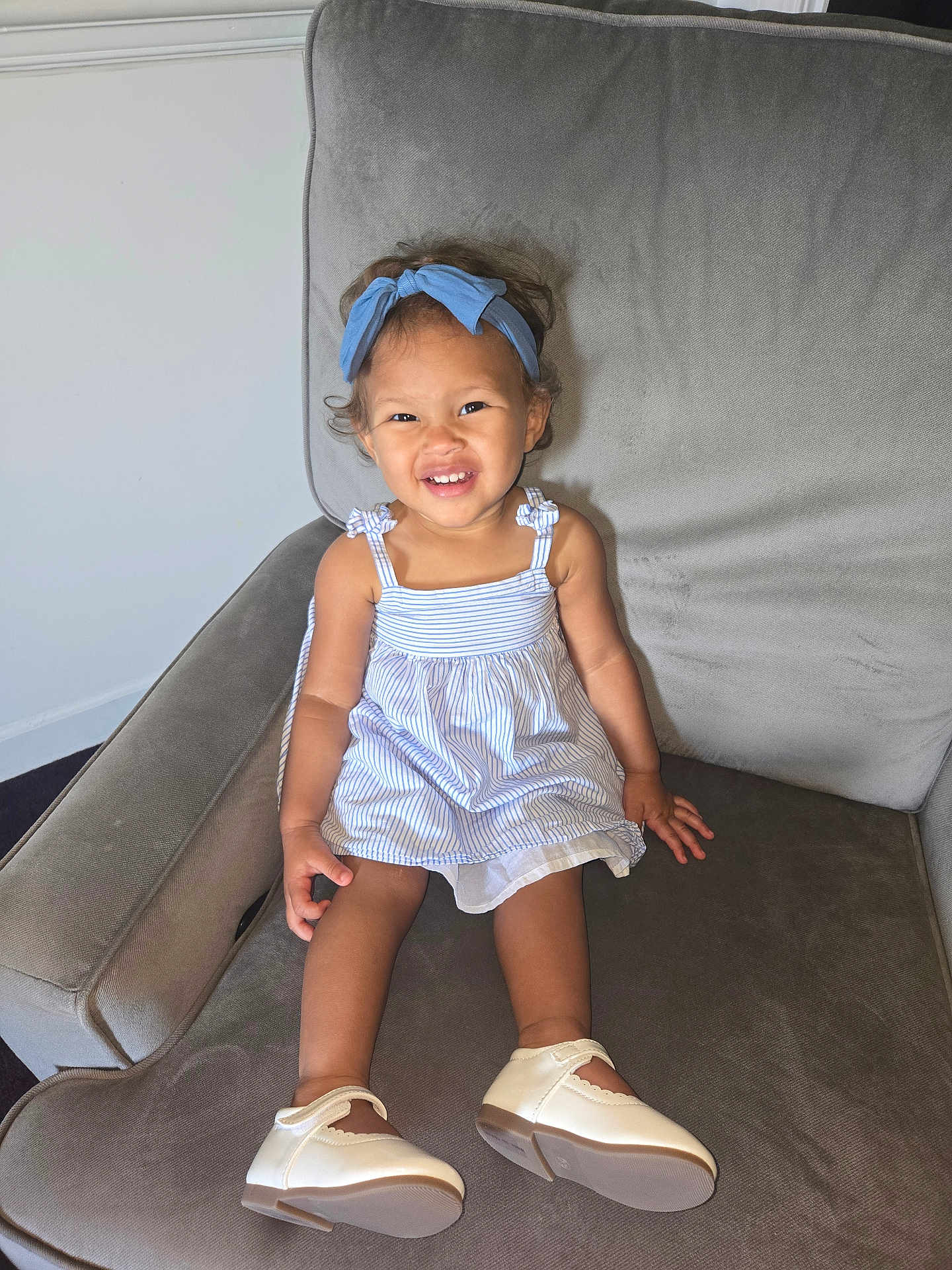 Magnolia is registered to the contest to win money with this photo: toddler, child, smile, dress, headband, blue, shoes, armchair, furniture, indoor, happy, person, footwear, cute, young_child, portrait, seated, clothing, hair, skin