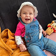Anastasia a rejoint le concours — aidez-le/la à gagner de superbes lots ! baby, blanket, child, clothing, couch, cozy, cute, denim_overalls, face, happy, indoor, infant, person, pink_shirt, plush_toy, portrait, seated, smiling, soft_toys, white_hat