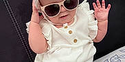 Anastasia a rejoint le concours — aidez-le/la à gagner de superbes lots ! accessory, baby, bed, bedding, casual, child, cute, fashion, green_pants, hand, hat, headwear, indoor, infant, patterned_pants, portrait, sitting, smiling, sunglasses, white_clothing