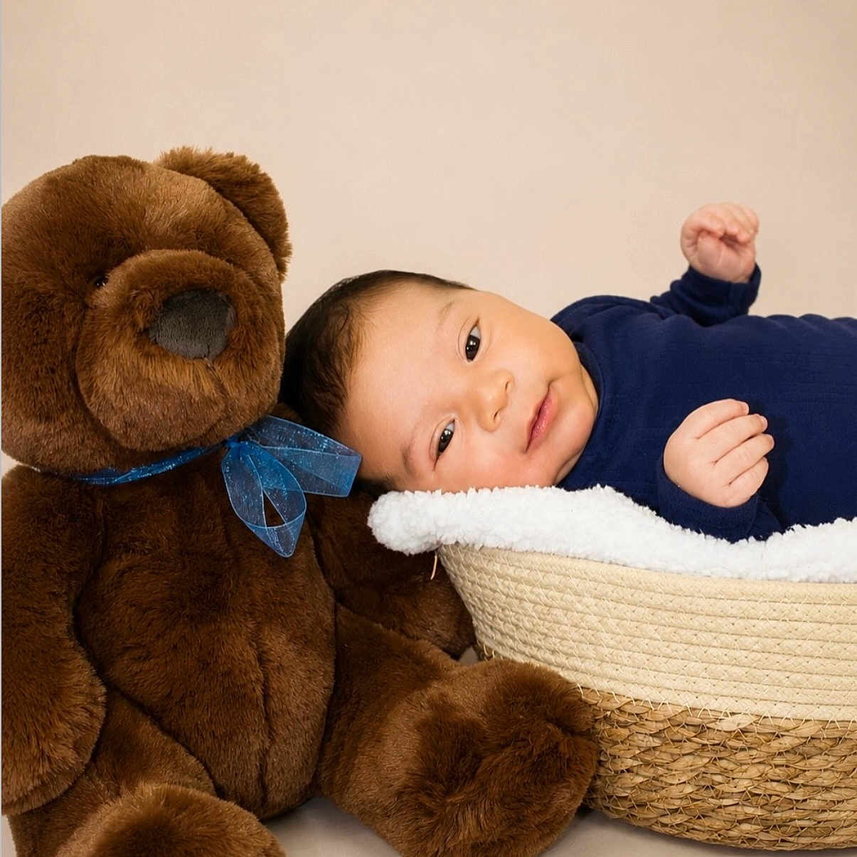Milan is registered to the contest to win money with this photo: baby, basket, blue_clothing, brown, child, cute, face, hands, indoor, infant, lying_down, nursery, photography, portrait, smiling, soft_lighting, studio, stuffed_animal, teddy_bear, woven_basket