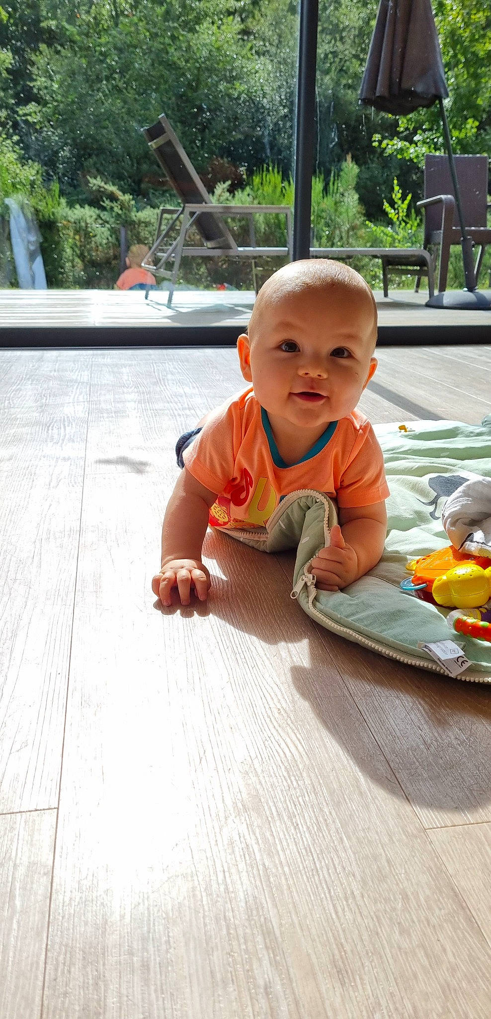Thilio participe au concours pour gagner de l'argent avec cette photo : baby, baby_toddler_clothing, child, crawling, floor, flooring, fun, grass, happy, hardwood, leisure, person, plant, recreation, sitting, skin, smile, toddler, tree, vacation