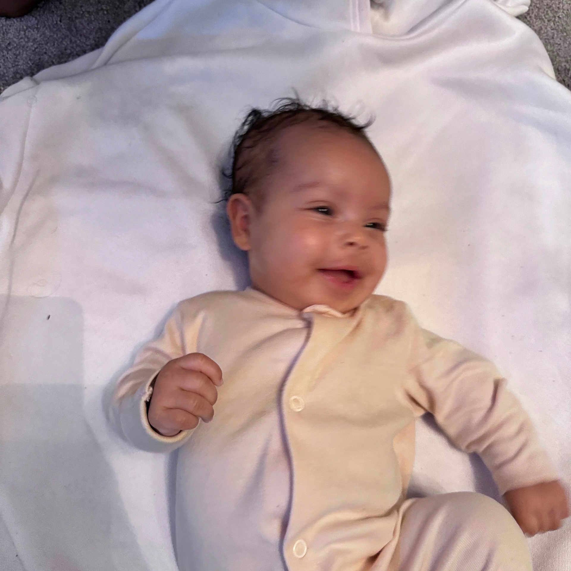 Kaleela is registered to the contest to win money with this photo: baby, infant, smiling, onesie, blanket, lying_down, happy, child, cute, indoors, skin, face, hand, motion_blur, young, small, toddler, soft, comfort, cozy