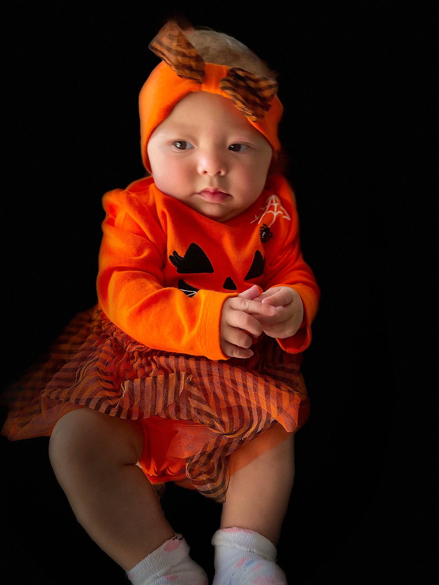 Mackenzie is registered to the contest to win money with this photo: baby, baby_toddler_clothing, costume, dress, face, fashion_design, flash_photography, hat, headgear, headwear, human_leg, iris, jewellery, knee, orange, peach, person, sitting, sleeve, sock