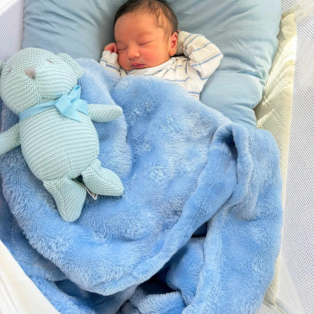 Reyav joined the competition — help win amazing prizes! newborn, baby, sleeping, crib, bassinet, blanket, blue, stuffed_animal, bunny, toy, pillow, infant, portrait, indoors, nursery, cozy, peaceful, swaddled, mesh, bedding