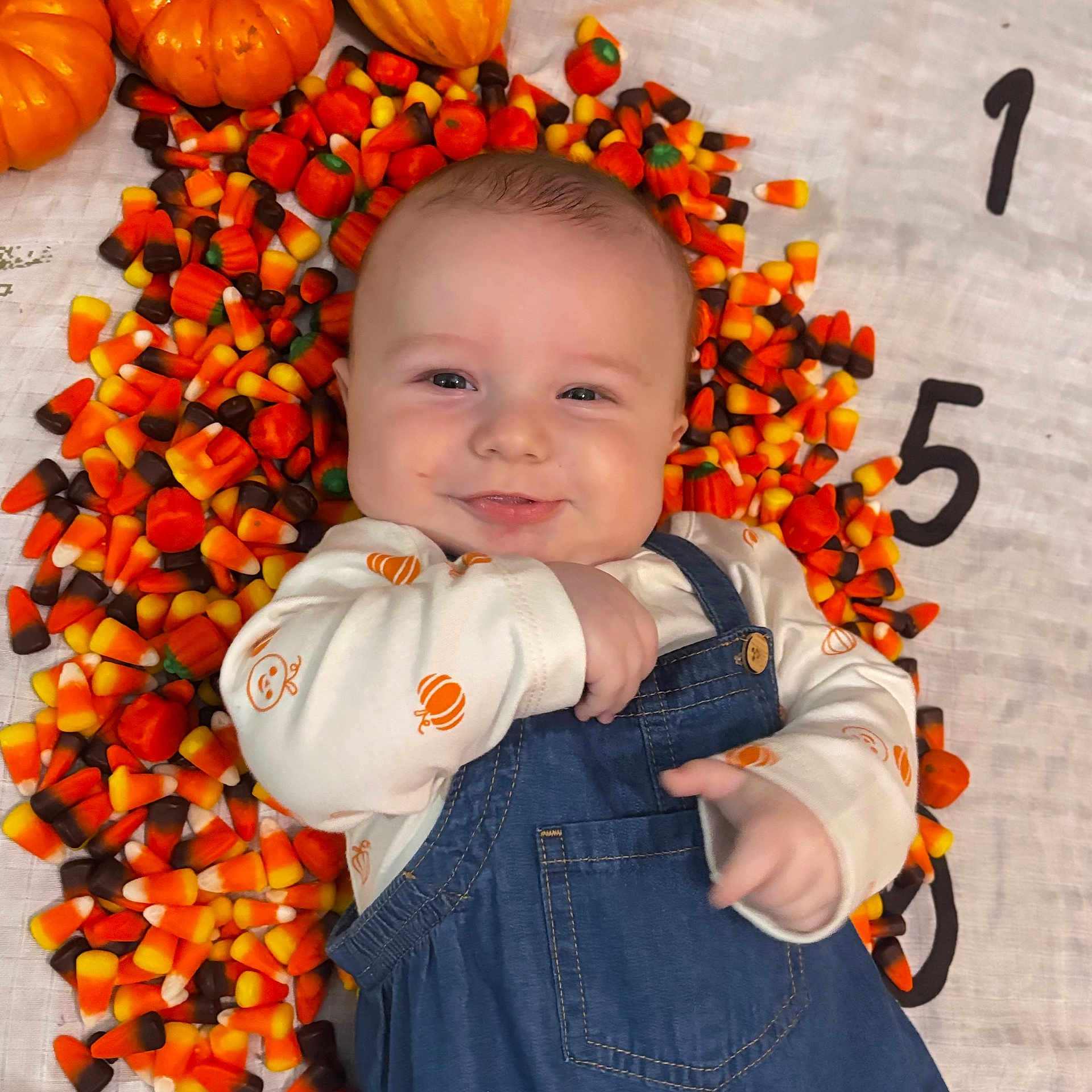 Oliver is registered to the contest to win money with this photo: baby, citrusfruit, clothing, face, food, fruit, happy, head, jeans, orange, pants, person, photography, plant, portrait, produce, pumpkin, smile, squash, vegetable