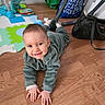 baby, bag, child, crawling, eyes, face, floor, green_clothing, hands, happy, hardwood_floor, onesie, play_area, playmat, room, smiling, soft_toys, stroller, toy_elephant, wood_texture