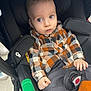 baby, black_cushion, buttoned_shirt, casual_clothing, child, curious, cute, face, green_bottle_holder, hands, indoor, infant, orange_booties, plaid_shirt, portrait, seat_belt, seated, stroller, wide_eyes, young_child