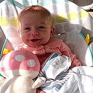 Emily joined the competition — help win amazing prizes! baby, infant, smiling, plush_toy, mushroom_toy, blanket, baby_seat, clothing, pink_outfit, happy, indoor, soft_toys, child, person, cute, comfort, sunlight, shadow, portrait, relaxing