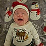 baby, smiling, santa_hat, sweater, moose, penguin, blanket, snowman, holiday, christmas, cute, infant, happy, clothing, face, child, lying_down, indoor, festive, cozy