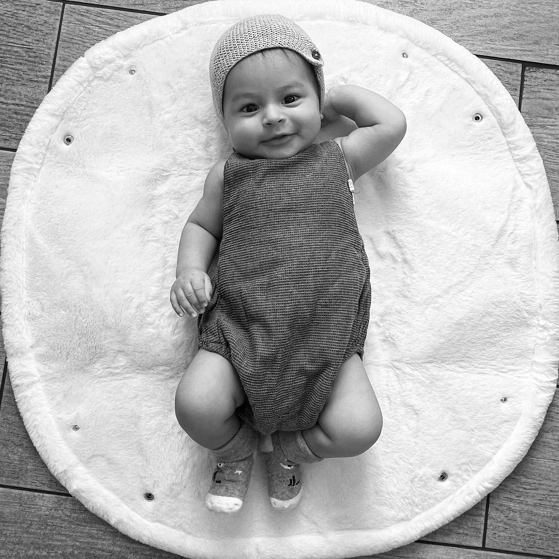 Jacques Isaac participe au concours pour gagner de l'argent avec cette photo : baby, black_and_white, child, cozy, cute, floor, fluffy_mat, happy, headwear, indoor, infant, knit_cap, lying_down, onesie, portrait, relaxed, smile, socks, soft_texture, wooden_floor