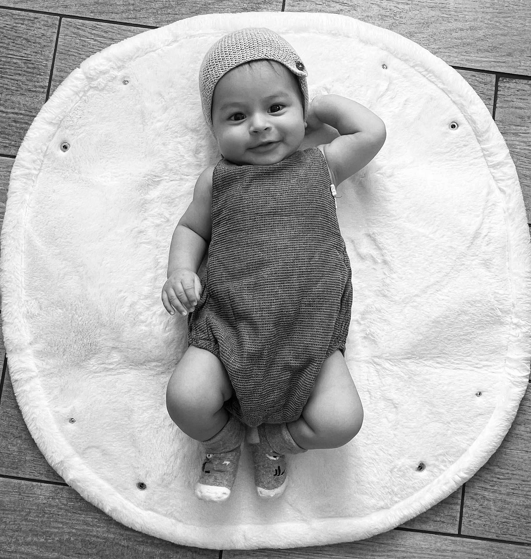 Jacques Isaac participe au concours pour gagner de l'argent avec cette photo : baby, infant, smile, knit_cap, onesie, socks, fluffy_mat, floor, wooden_floor, black_and_white, portrait, child, cute, happy, relaxed, lying_down, indoor, cozy, soft_texture, headwear