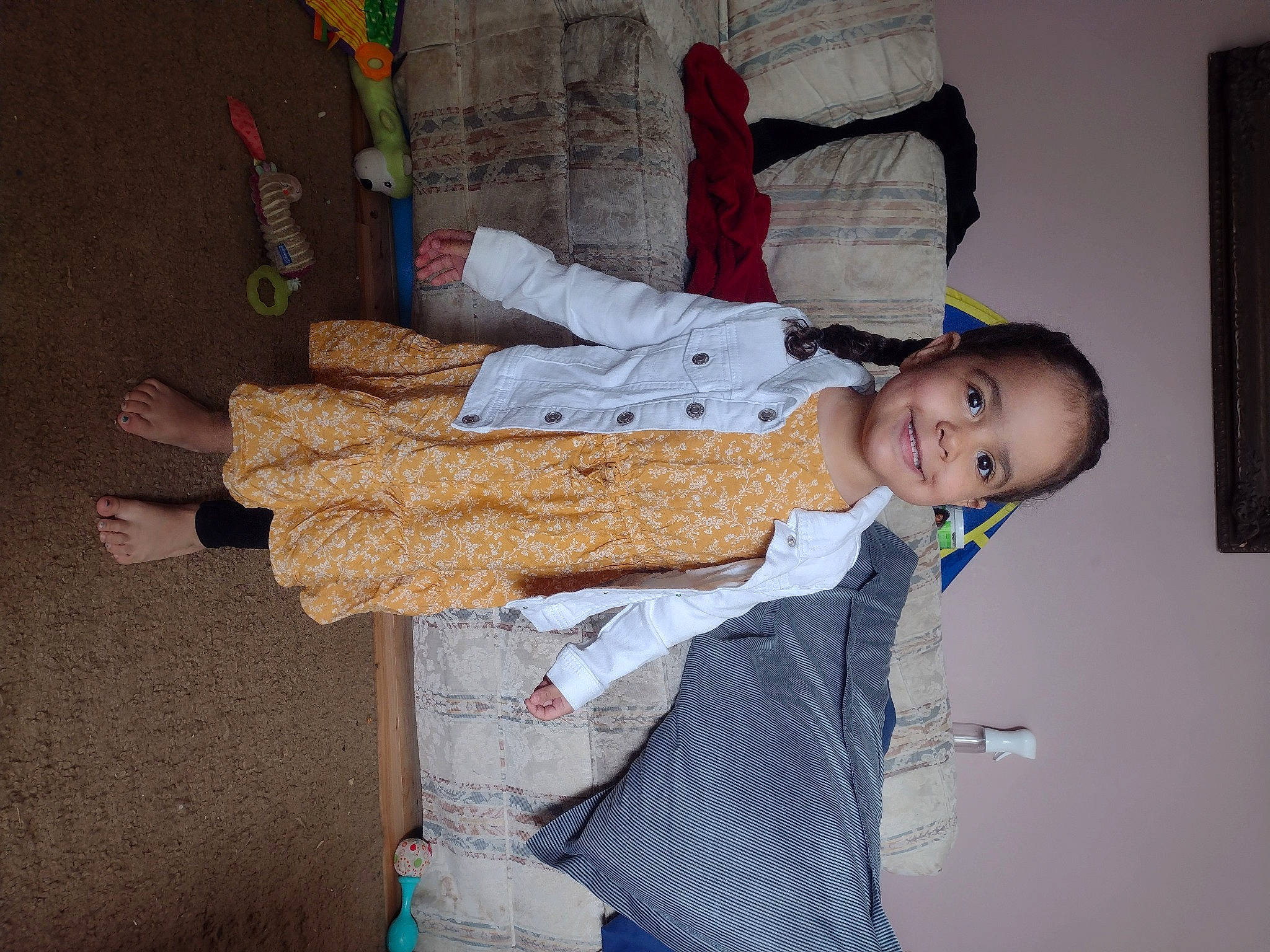 Adalyn is registered to the contest to win money with this photo: baby, baby_toddler_clothing, cheek, child, comfort, fun, joy, linens, pattern, person, picture_frame, room, sitting, sleeve, smile, standing, thread, toddler, wood, wool