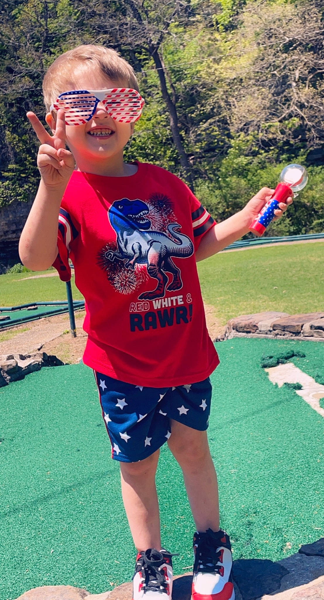 Kayleb is registered to the contest to win money with this photo: active_shorts, board_short, clothing, cool, eyewear, fun, goggles, grass, happy, joy, leisure, person, red, shorts, sleeve, smile, summer, sunglasses, t_shirt, trunks