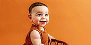 Tyree is registered to the contest to win money with this photo: baby, infant, smiling, wicker_basket, orange_background, cute, child, portrait, sitting, happy, studio, one_person, young, indoors, clothing, skin, face, eyes, mouth, toes