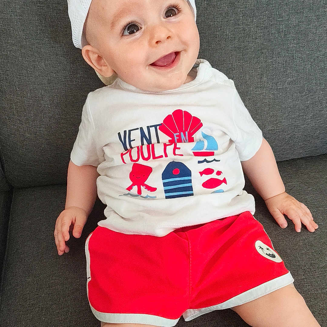 Swan participe au concours pour gagner de l'argent avec cette photo : baby, casual, child, clothing, comfortable, couch, cute, face, hands, happy, indoor, infant, legs, portrait, red_shorts, sitting, smiling, tshirt, white_cap, young