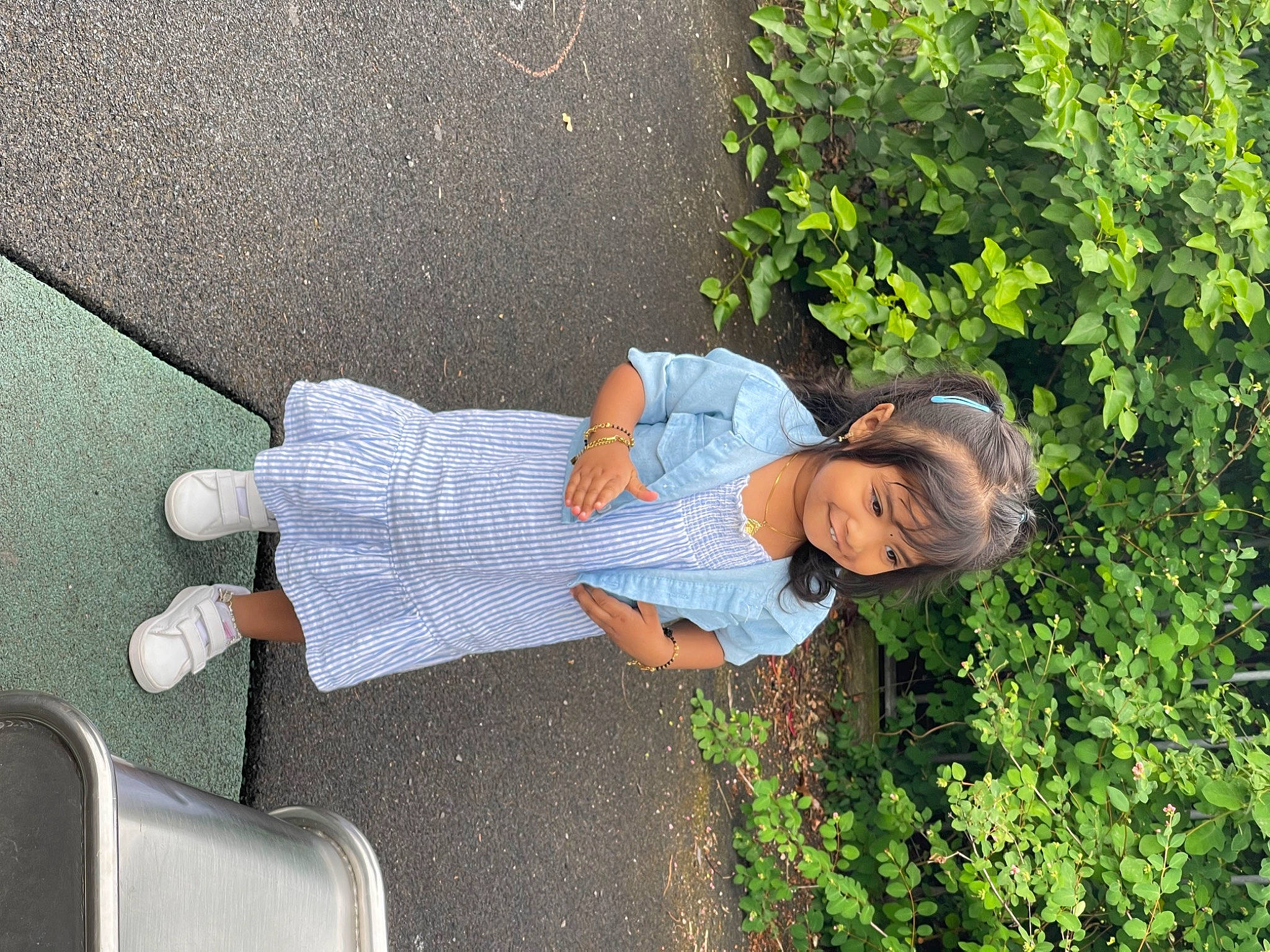 Iniya joined the competition — help win amazing prizes! annual_plant, asphalt, child, fun, garden, grass, groundcover, hat, human_leg, joy, landscape, leisure, people_in_nature, person, plant, shrub, sidewalk, sitting, sunglasses, thigh