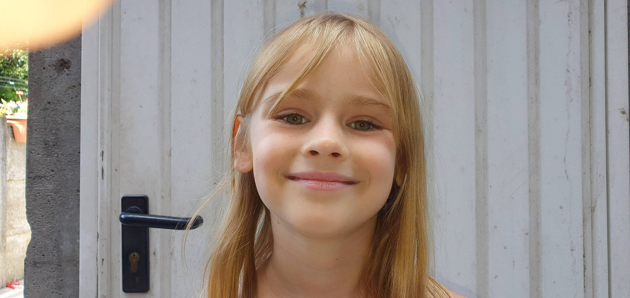 Milena participe au concours pour gagner de l'argent avec cette photo : bangs, blond, brown_hair, cheek, chin, door, door_handle, eye, eyebrow, eyelash, facial_expression, happy, iris, jaw, joy, layered_hair, lip, nose, person, smile