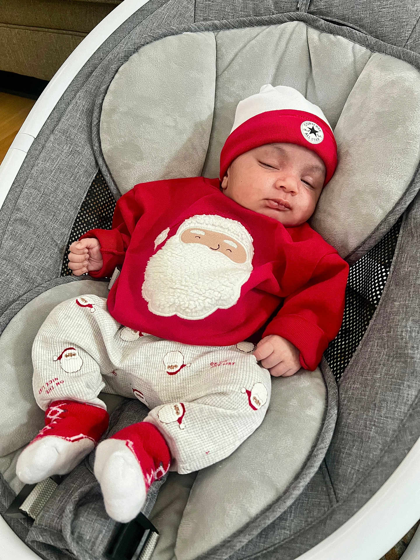 Dariel is registered to the contest to win money with this photo: baby, infant, sleeping, red_clothing, santa_clothing, hat, baby_rocker, cushion, gray_fabric, holiday, festive, cute, indoors, peaceful, cozy, child, footwear, sock, smiling_face_on_clothing, relaxing
