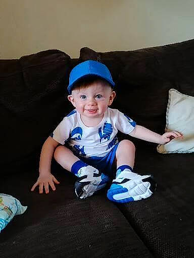 Markus is registered to the contest to win money with this photo: baby, baby_toddler_clothing, child, comfort, couch, electric_blue, flash_photography, fun, grass, happy, hat, human_leg, person, pillow, sitting, sleeve, smile, sock, t_shirt, thumb