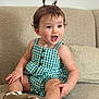 Angelina joined the competition — help win amazing prizes! toddler, child, smiling, sitting, couch, green_checkered_dress, sandals, pigtails, happy, indoors, cute, expression, playful, young_child, person, face, skin, hair, comfort, furniture