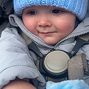 Theo is registered to the contest to win money with this photo: baby, child, blue_hat, knit_hat, blanket, winter_clothing, jacket, bundle_up, cute, face, hand, infant, warm, soft_texture, close_up, portrait, baby_boy, outdoor, seatbelt, car_seat