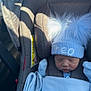 newborn, baby, car_seat, hat, blue, blanket, infant, sleeping, pom_poms, clothing, child, person, seatbelt, interior, car, sunlight, shadow, cozy, cute, bundle