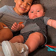 Catrell is registered to the contest to win money with this photo: baby, child, closeup, clothing, couch, curly_hair, cute, family, footwear, happy, home, indoor, person, portrait, relaxing, sibling, sitting, smiling, striped_clothes, toddler