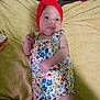 Juniper is registered to the contest to win money with this photo: baby, blanket, child, clothing, colorful, cute, face, floral_pattern, headband, indoor, infant, lying_down, person, red, remote_control, romper, skin, small, soft_texture, young