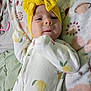 Juniper is registered to the contest to win money with this photo: baby, blanket, child, closeup, comfort, cute, expression, face, floral, headband, indoors, infant, lemon_pattern, lying_down, onesie, portrait, sleepwear, small_hand, soft, yellow_bow
