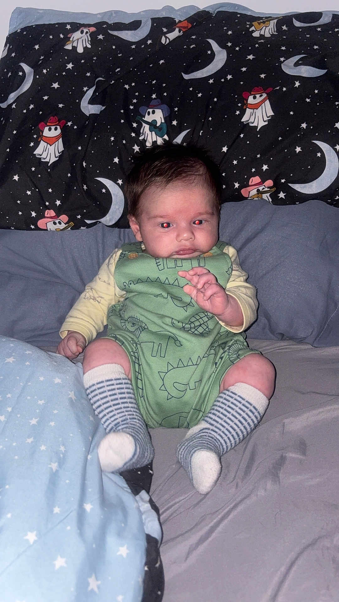 Leo joined the competition — help win amazing prizes! baby, infant, bed, bedding, pillow, blanket, onesie, socks, dinosaur_pattern, stars, moon, sleepwear, indoor, person, face, hair, cute, child, sitting, flash