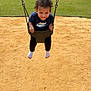 child, toddler, swing, playground, smile, happy, outdoor, grass, sand, sunny, curly_hair, clothing, socks, person, recreation, fun, daytime, park, holding, playing