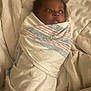 baby, infant, wrapped, blanket, hospital_blanket, bed, soft, newborn, face, cute, lying_down, indoors, child, person, swaddled, looking, young, sleepy, cozy, comfort