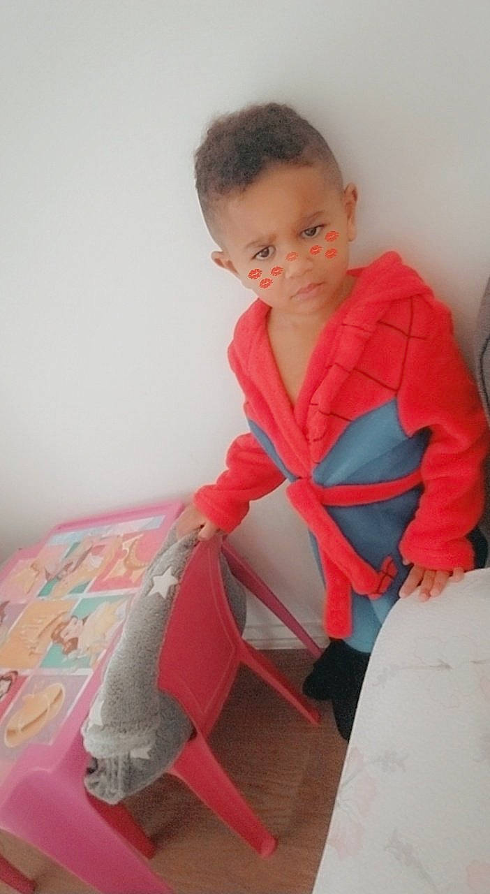 Kassim participe au concours pour gagner de l'argent avec cette photo : baby, baby_products, baby_toddler_clothing, carmine, chair, comfort, flooring, human_body, human_leg, joint, knee, linens, person, personal_protective_equipment, room, shoulder, sitting, sleeve, t_shirt, thigh