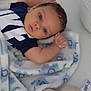 Sebastian is registered to the contest to win money with this photo: baby, blue_eyes, blanket, plush_toy, soft_toy, cute, infant, lying_down, indoors, clothing, person, face, hand, head, expression, comfort, resting, child, toddler, sleep_area