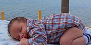 Sebastian joined the competition — help win amazing prizes! baby, sleeping, plaid_shirt, blanket, outdoor, beach, water, tree_trunk, peaceful, infant, soft_texture, blue_sky, nature, cute, child, portrait, relaxation, calm, sock, toddler