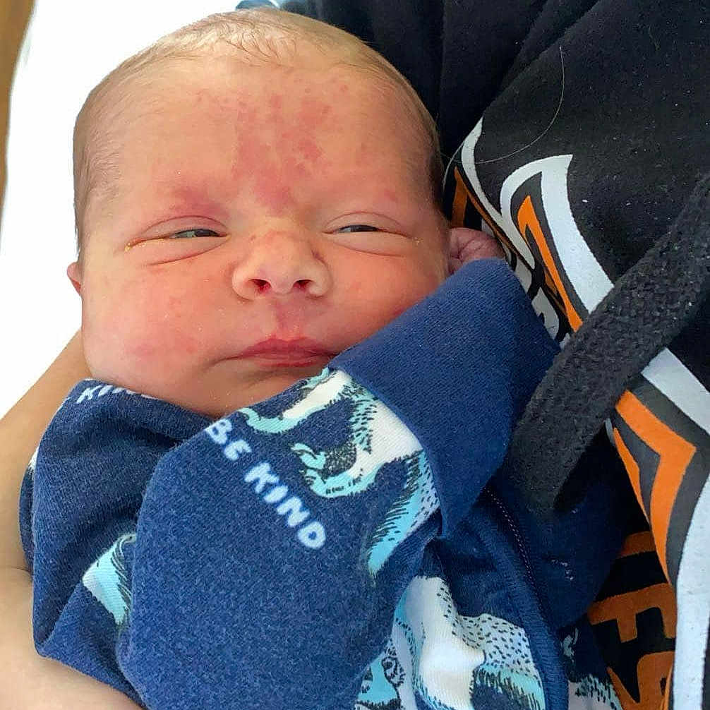 Aiden is registered to the contest to win money with this photo: architecture, baby, blanket, building, clothing, coat, face, glove, head, hospital, jacket, newborn, pants, person, photography, portrait, quilt, sleeping, t_shirt, towel