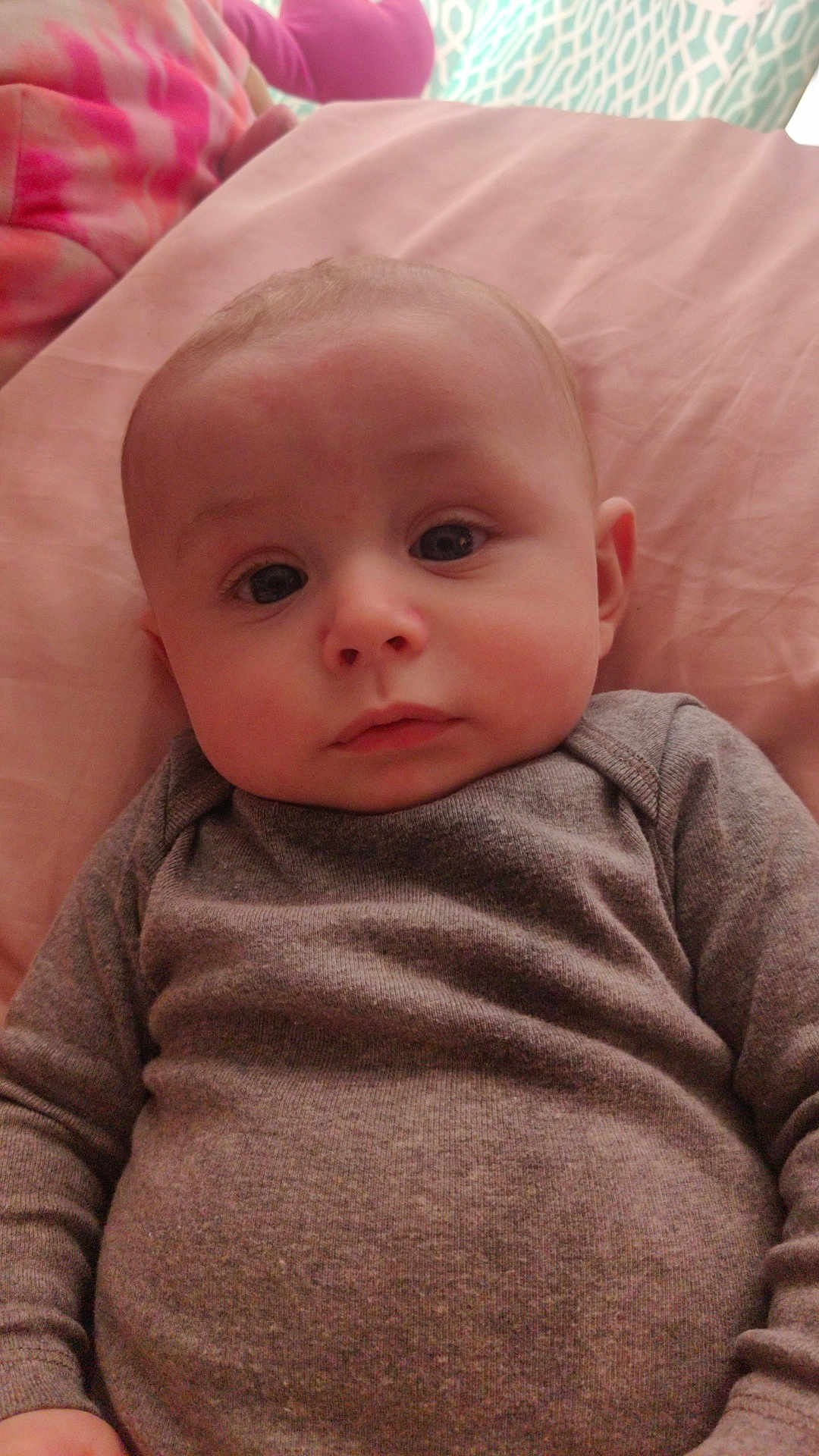 Jonathon is registered to the contest to win money with this photo: baby, infant, face, eyes, clothing, gray_sweater, lying_down, bed, blanket, pink, soft, child, cute, portrait, skin, head, young, indoors, expression, cozy