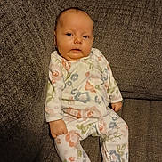 Athena joined the competition — help win amazing prizes! baby, infant, onesie, floral_pattern, couch, furniture, indoor, portrait, child, young_child, face, sitting, comfortable, soft_lighting, home, relaxing, cute, small_hands, footed_pajamas, expression