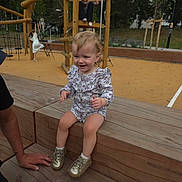 Nya participe au concours pour gagner de l'argent avec cette photo : toddler, child, playground, wood, bench, outdoor, clothing, shoes, smile, person, play, fun, park, wooden_structure, trees, daylight, happy, casual, young_child, activity