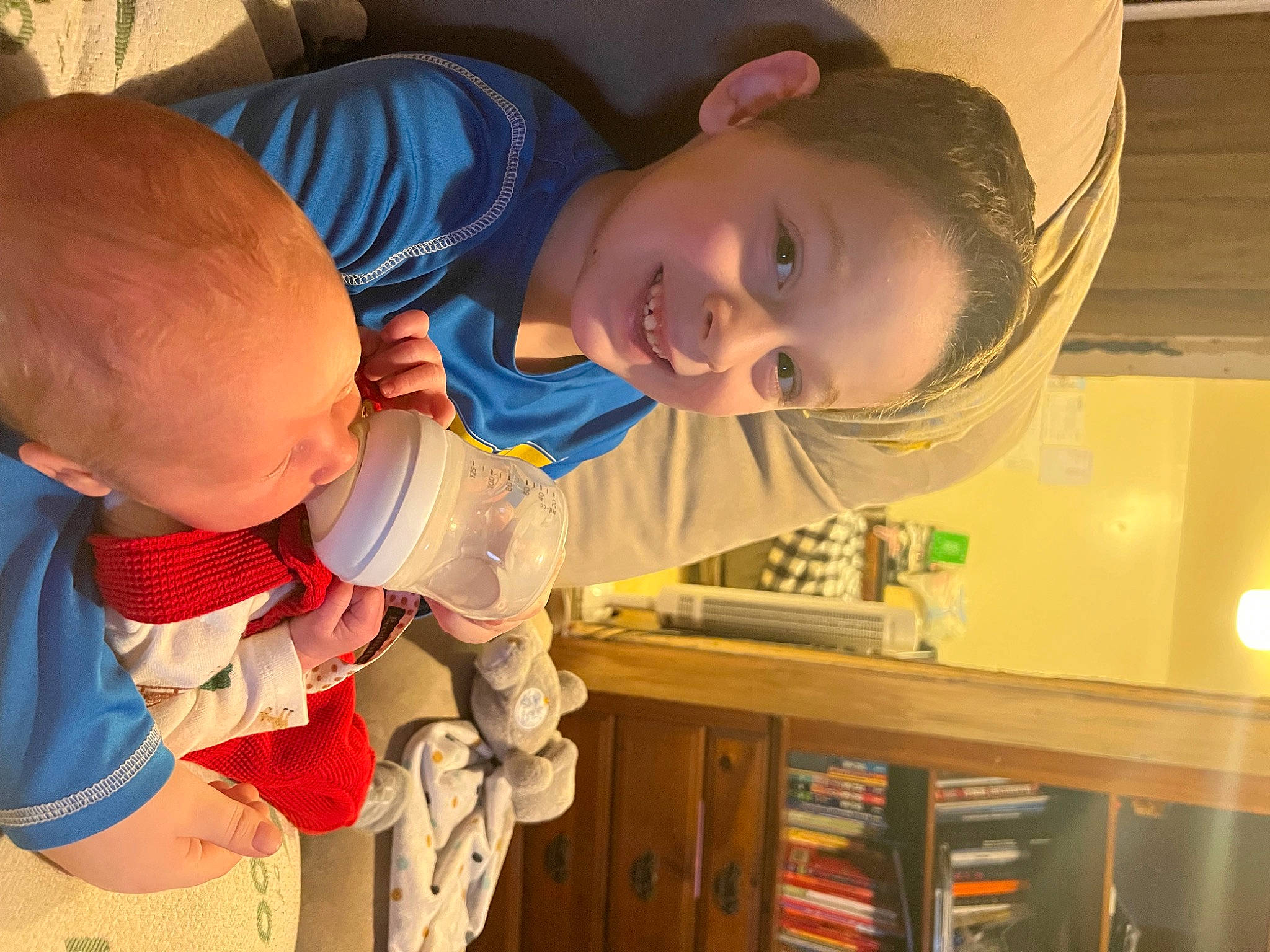 Damien is registered to the contest to win money with this photo: baby, baby_toddler_clothing, bookcase, cheek, child, finger, fun, happy, human_body, joy, mouth, nose, organ, person, play, room, shelf, sitting, smile, toddler